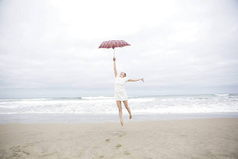 Woman playing with umbrella on beach