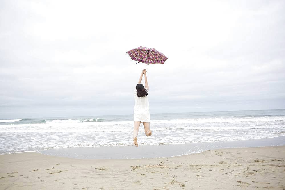 Woman playing with umbrella on beach