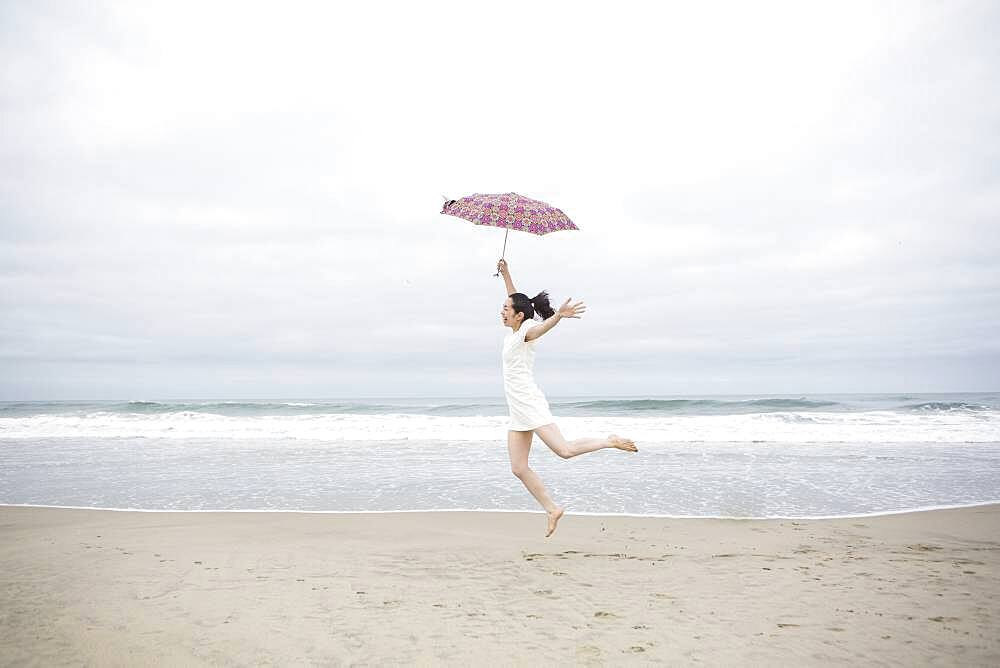 Woman playing with umbrella on beach