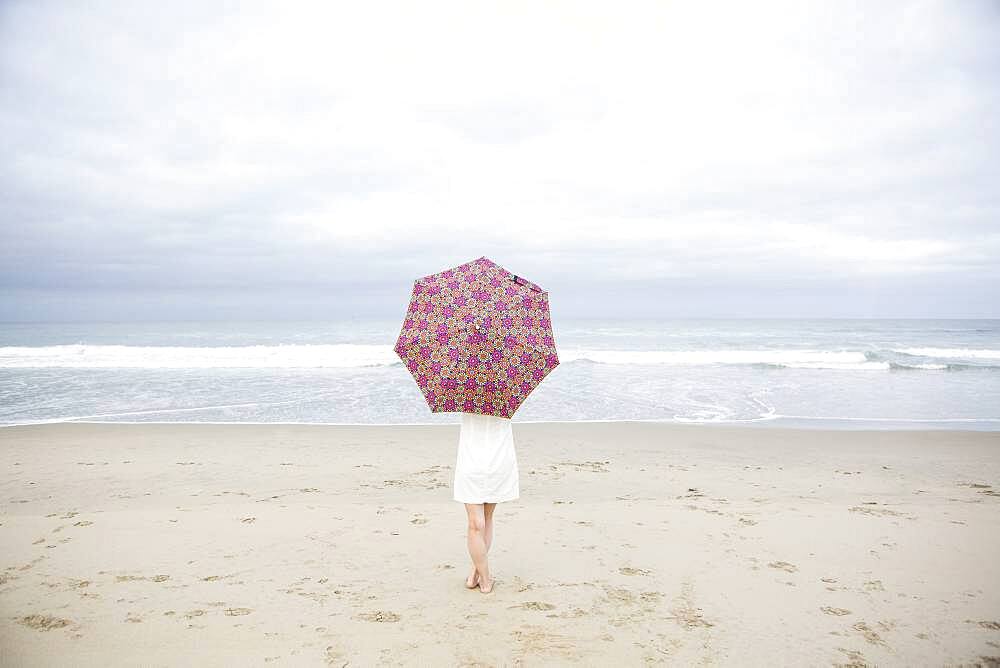 Woman standing with umbrella on beach