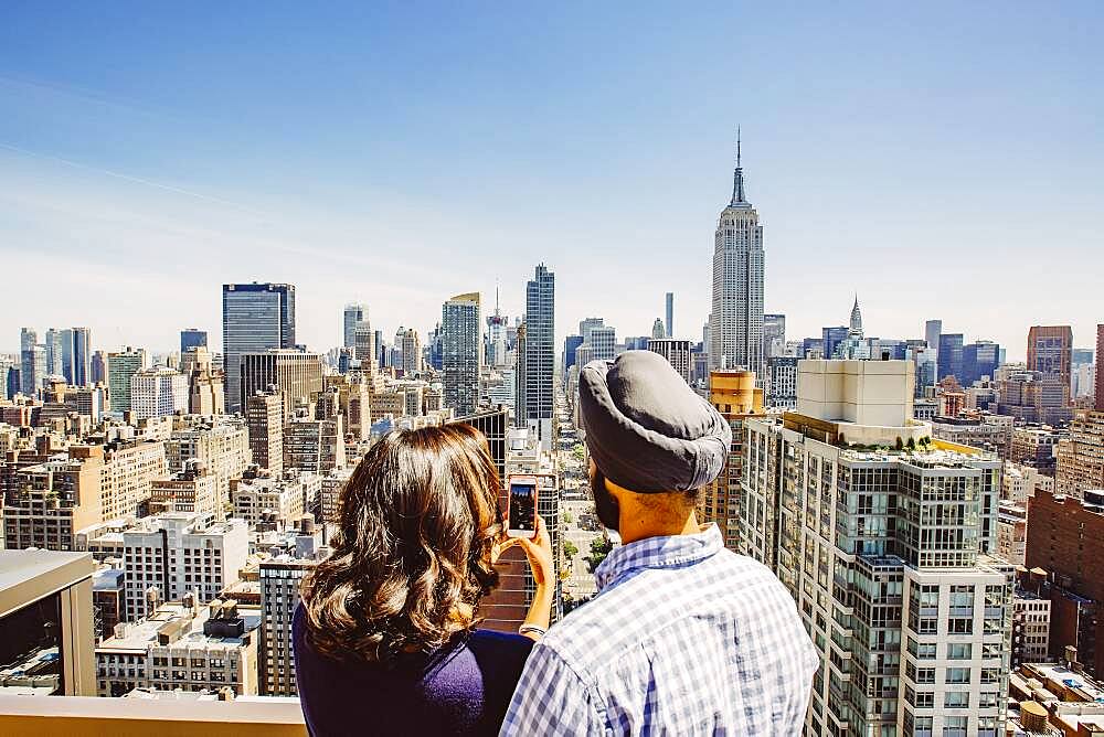 Indian couple taking cell phone photograph of New York cityscape, New York, United States