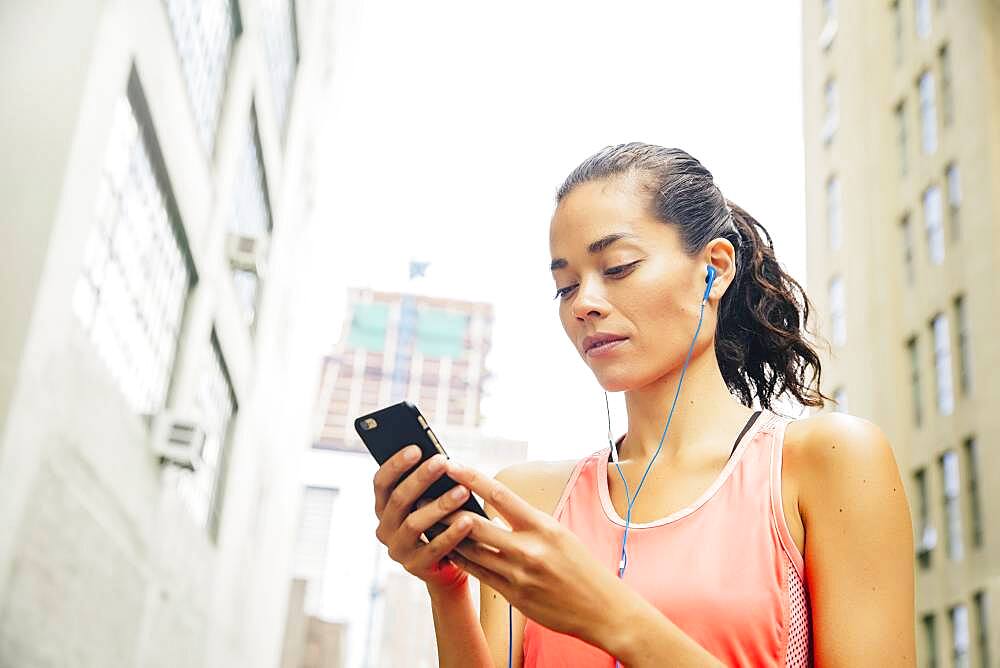 Mixed race athlete listening to mp3 player in city