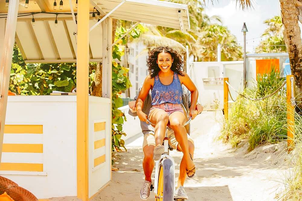 Couple riding bicycle on beach