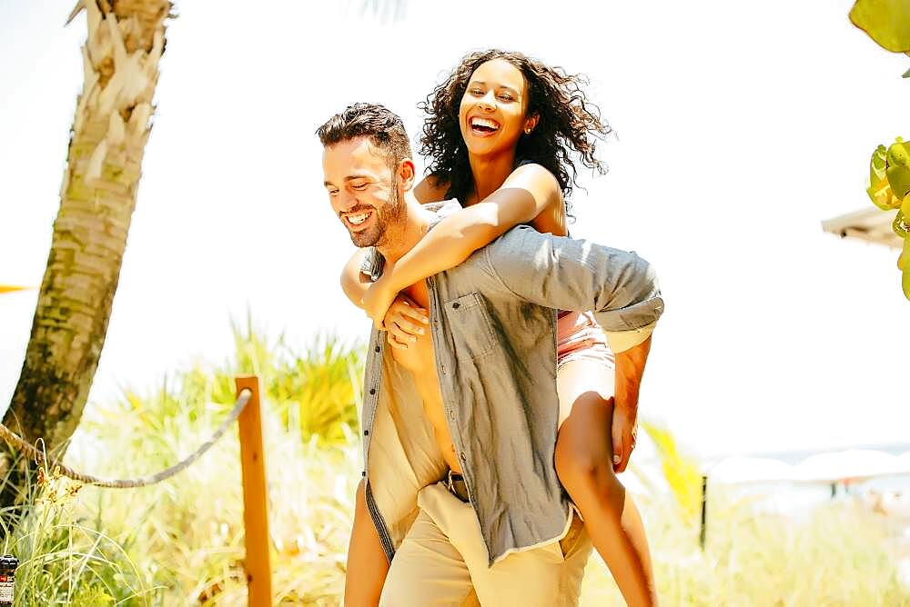 Man carrying girlfriend piggyback on beach