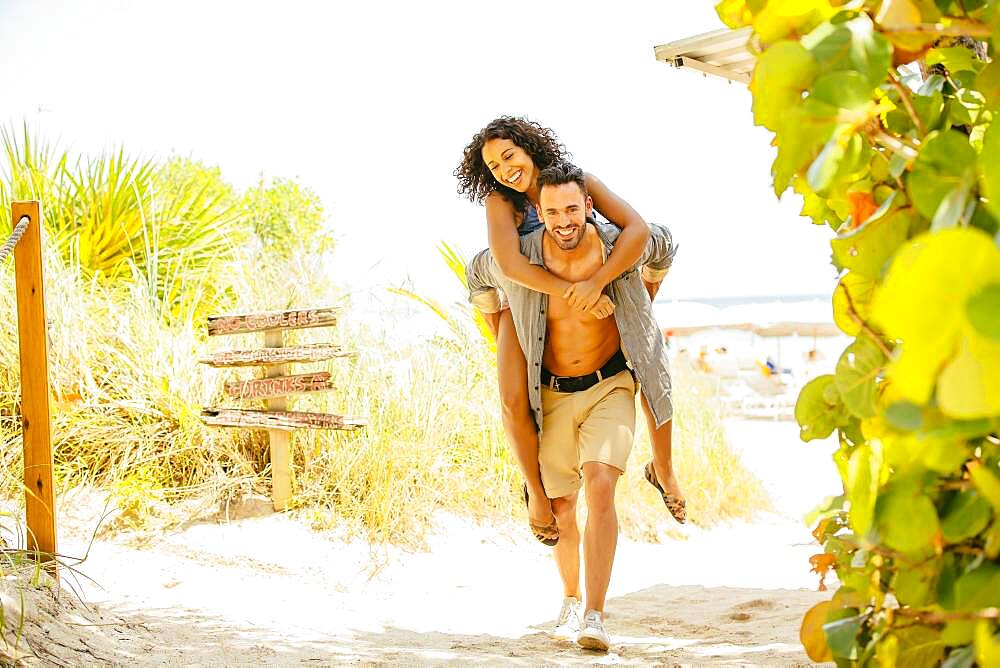 Man carrying girlfriend piggyback on beach