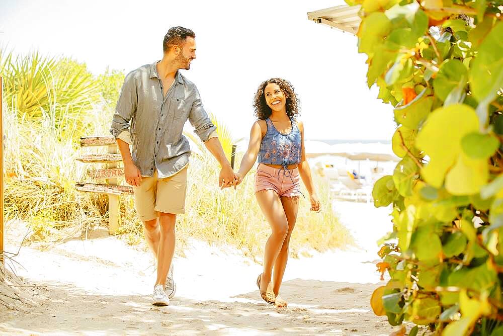 Couple holding hands and walking on beach