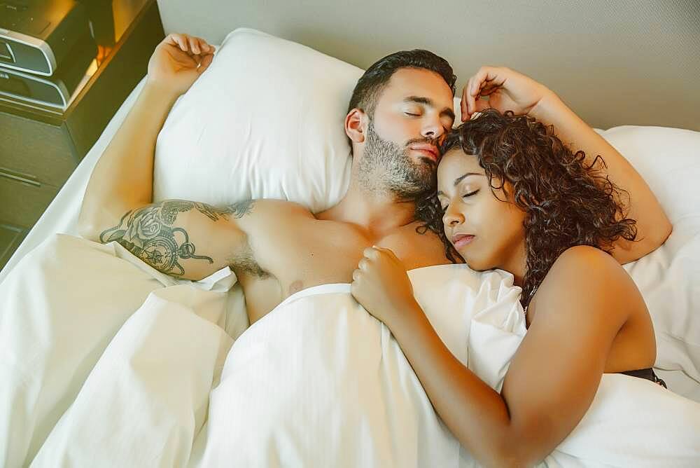 Sleeping couple hugging in bed