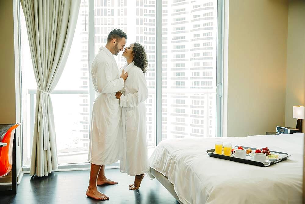 Couple hugging in bathrobes in hotel room