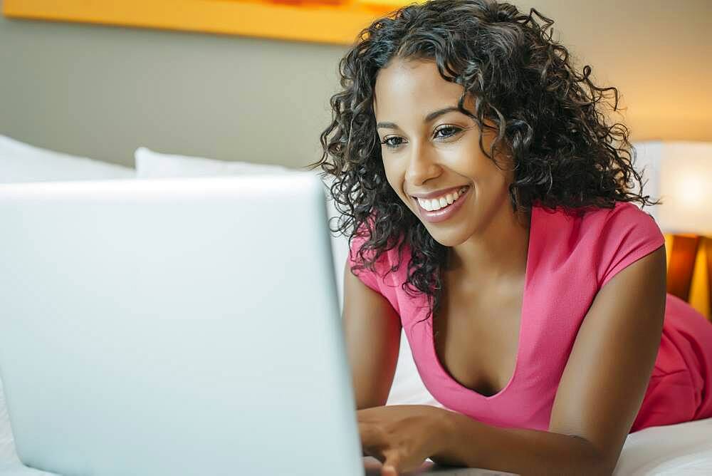 Woman using laptop on hotel bed