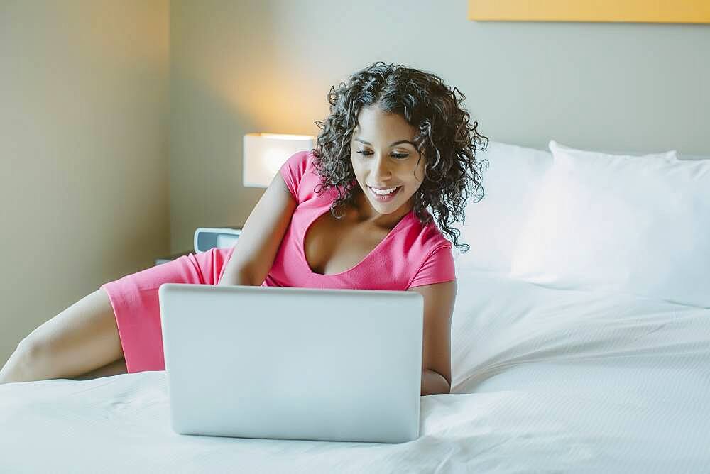 Woman using laptop on hotel bed