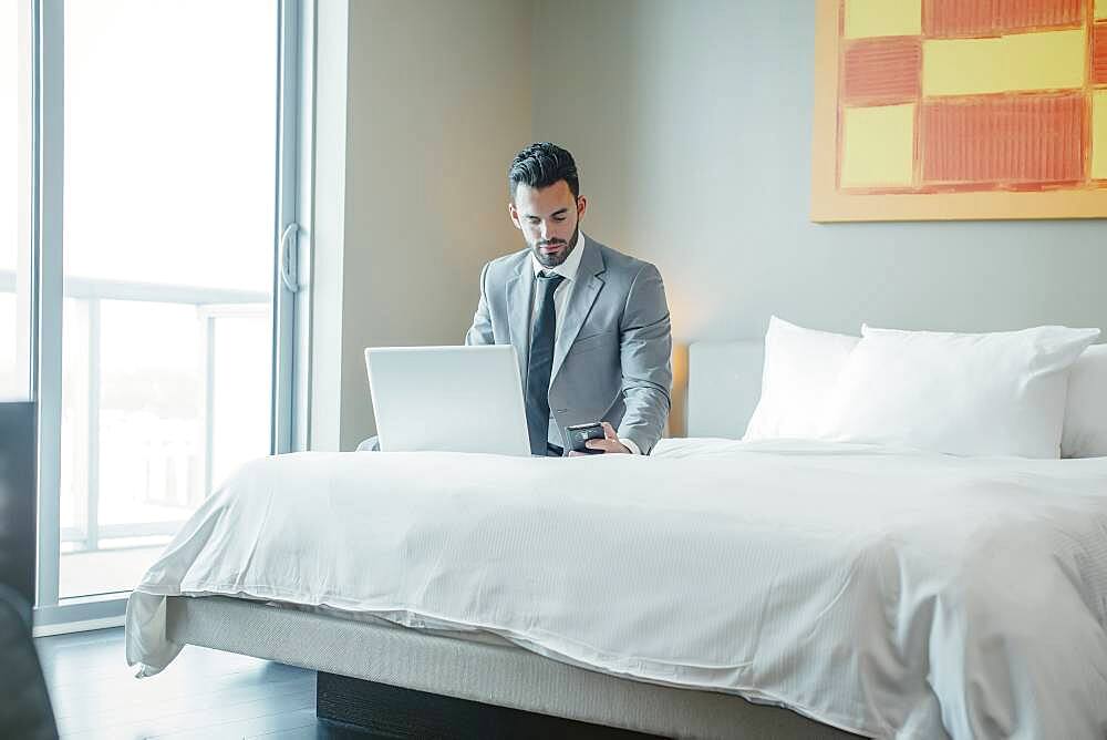 Businessman using laptop on hotel bed