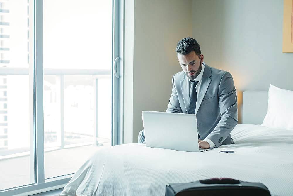 Businessman using laptop on hotel bed