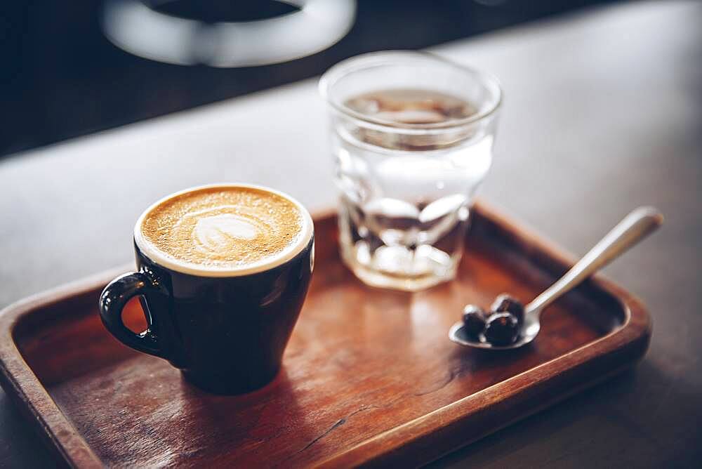 Tray of coffee, coffee beans and water in cafe