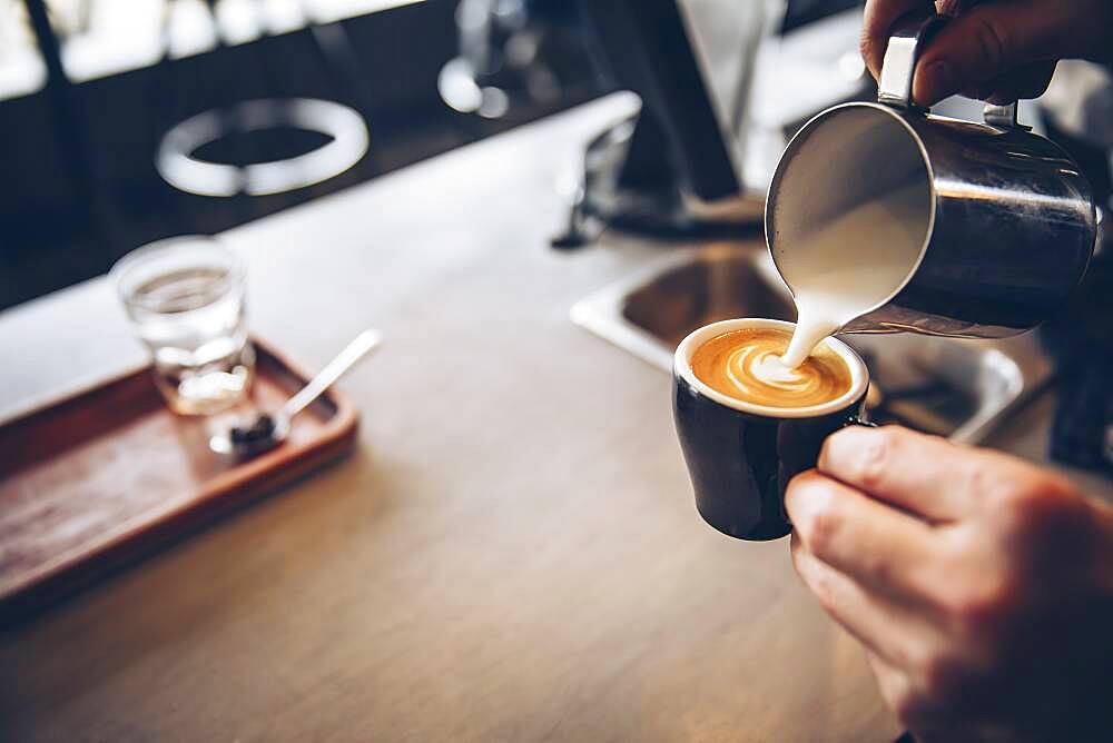 Caucasian barista pouring coffee drink in cafe