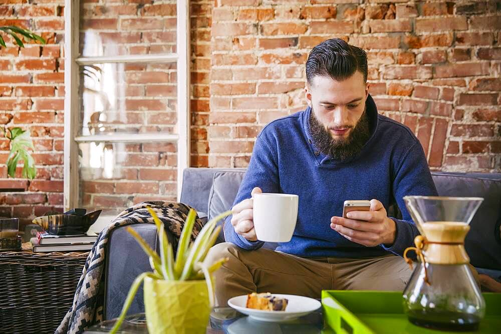 Caucasian man drinking coffee on sofa in living room