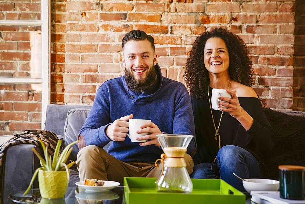 Couple drinking coffee on sofa in living room