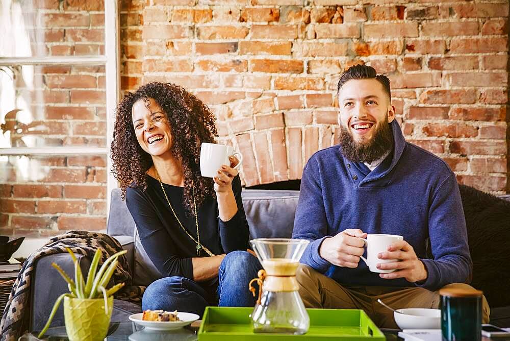 Couple drinking coffee on sofa in living room