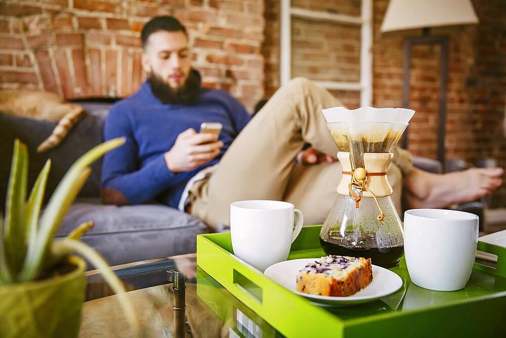 Man using cell phone with breakfast in living room