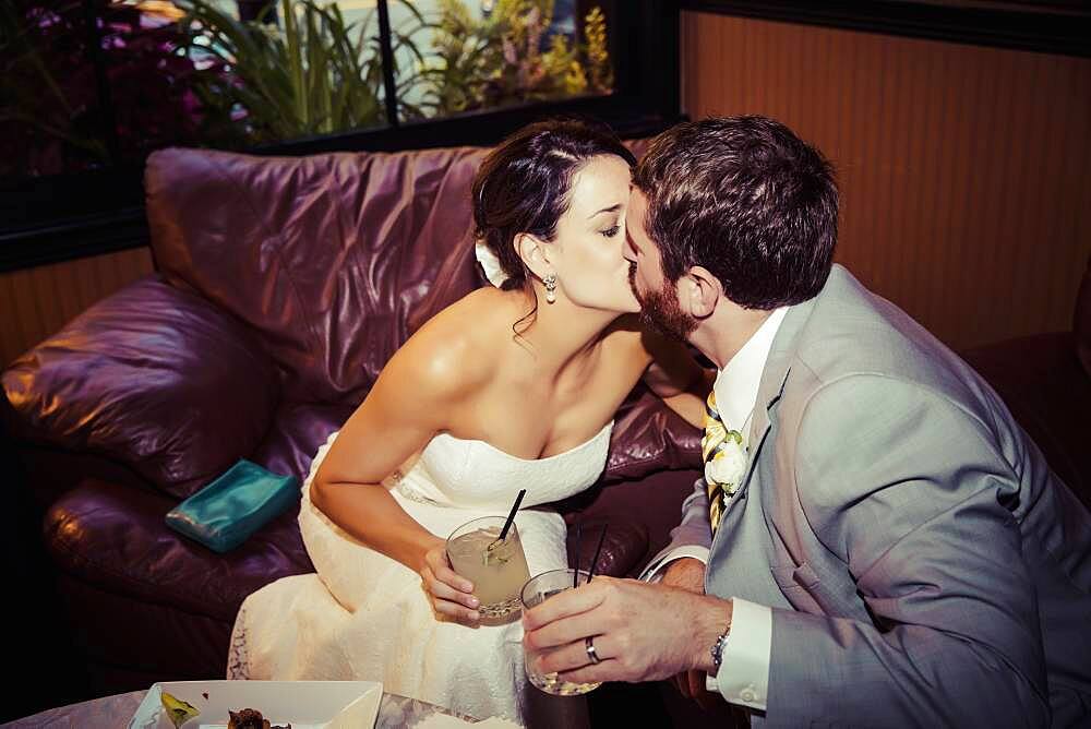 Caucasian bride and groom kissing in living room