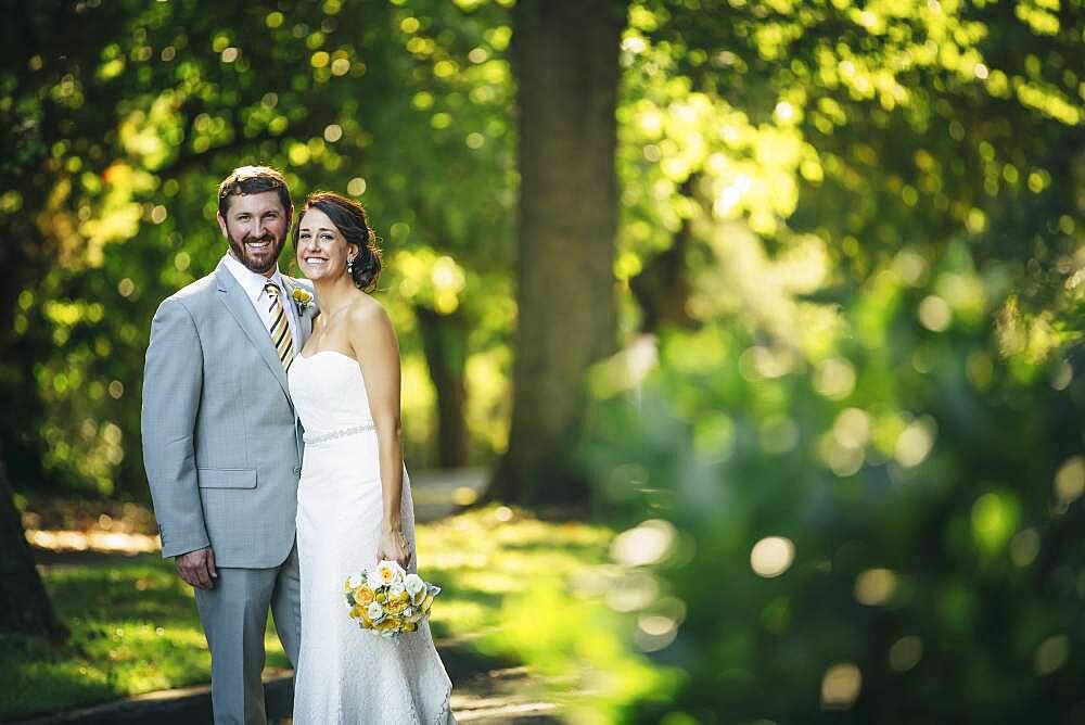 Caucasian bride and groom hugging on rural road