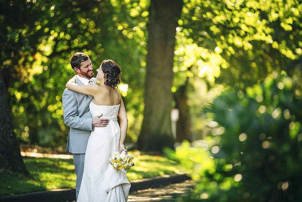 Caucasian bride and groom hugging on rural road