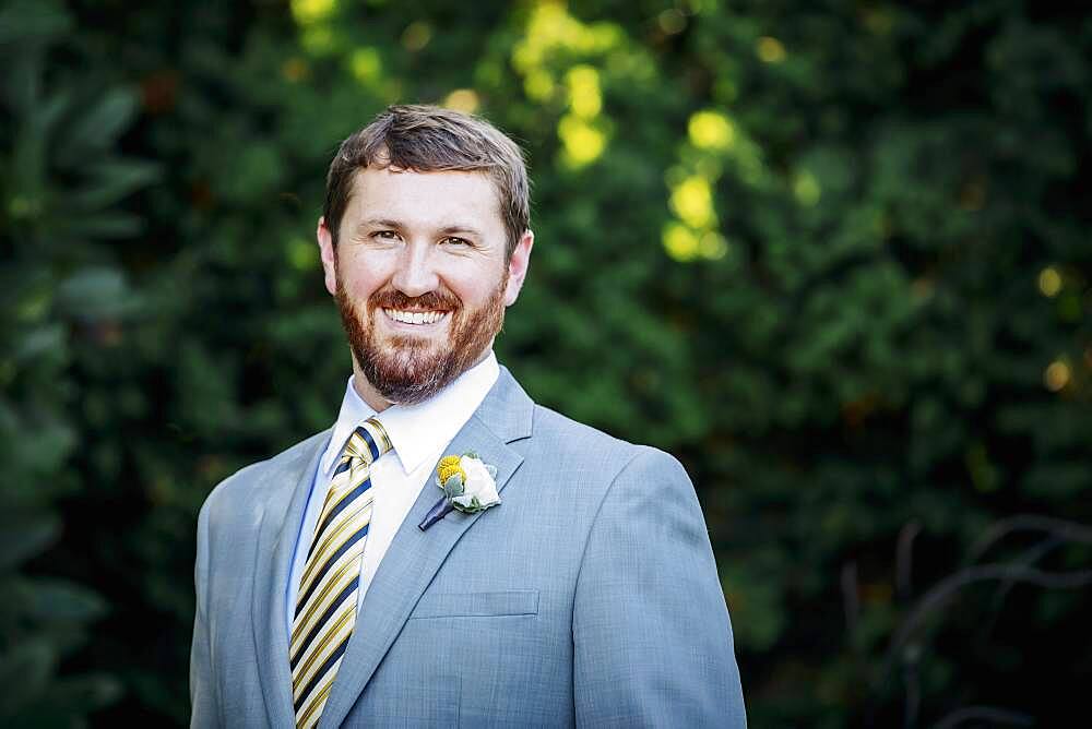 Caucasian groom smiling in garden