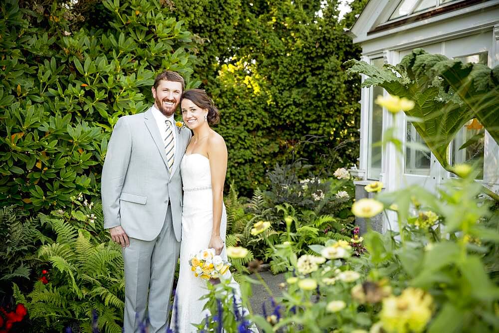 Caucasian bride and groom smiling in garden