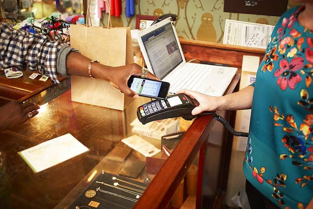 Woman using cell phone for payment in store