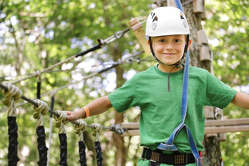 Caucasian boy balancing on rope bridge