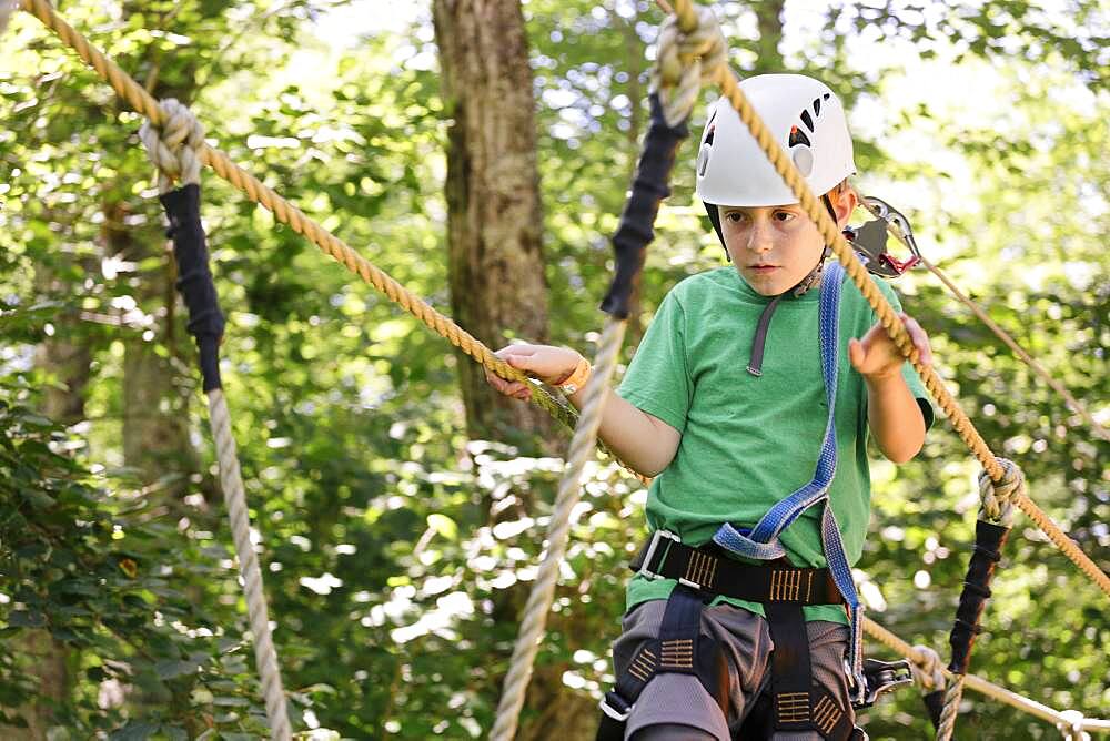 Caucasian boy balancing on rope bridge