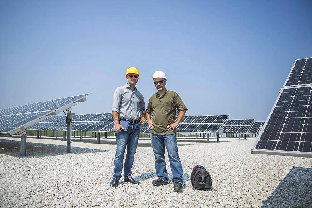 Caucasian technicians standing near solar panels