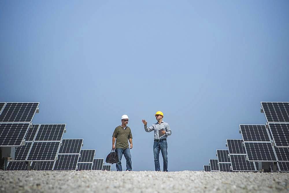 Caucasian technicians talking near solar panels