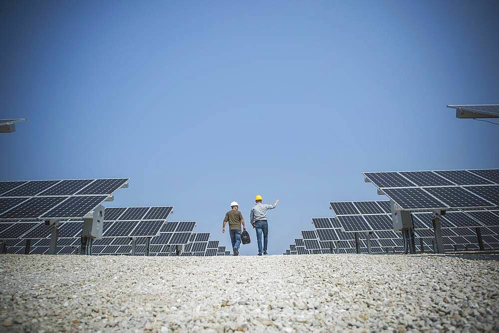 Caucasian technicians talking near solar panels