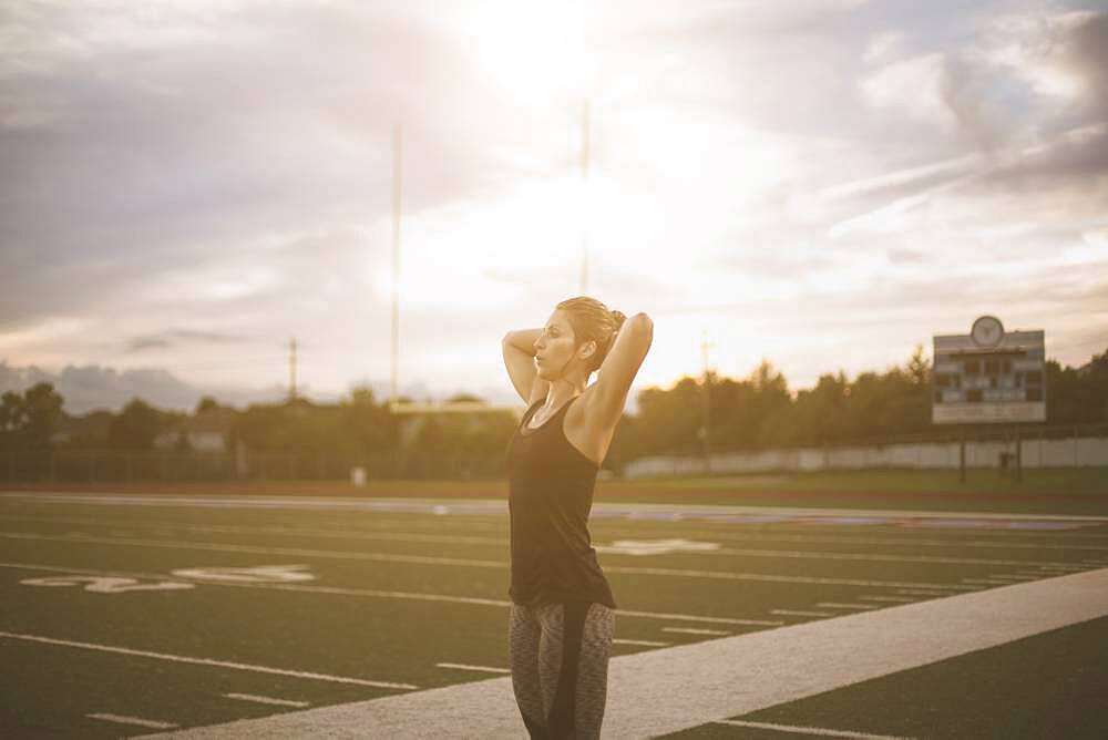 Caucasian athlete tying her hair up on sports field