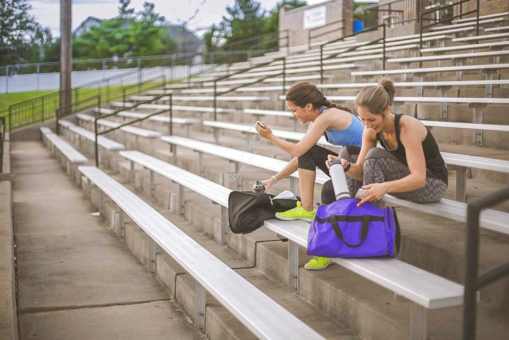 Women packing gym bags on bleachers