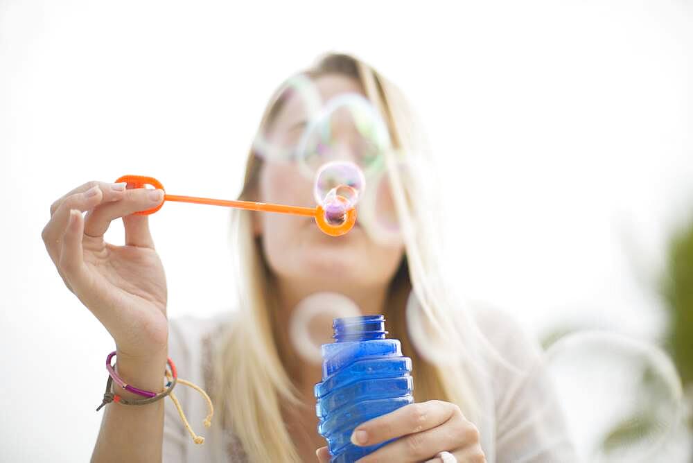 Caucasian woman blowing bubbles outdoors