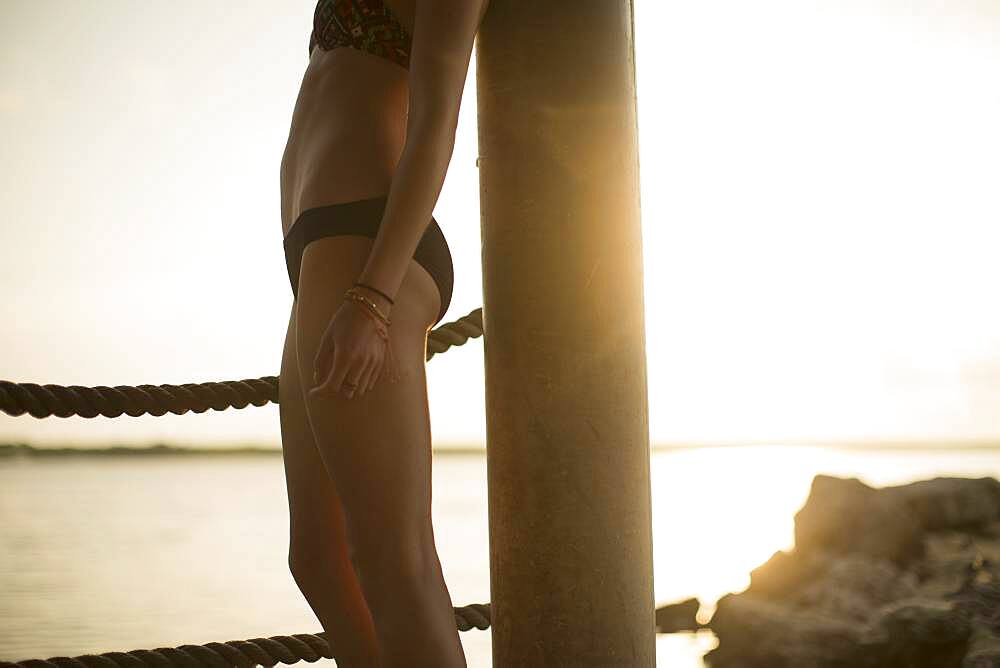 Caucasian woman standing by lake at sunset