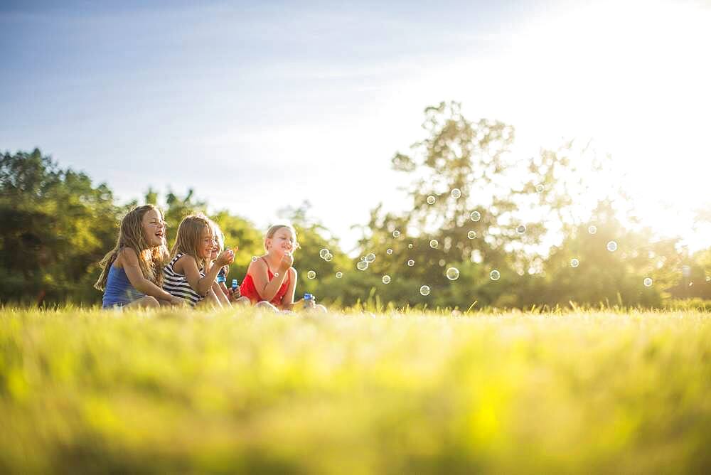 Girls blowing bubbles in grass field