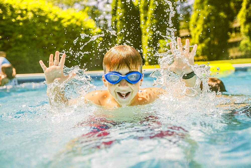 Boy splashing in swimming pool