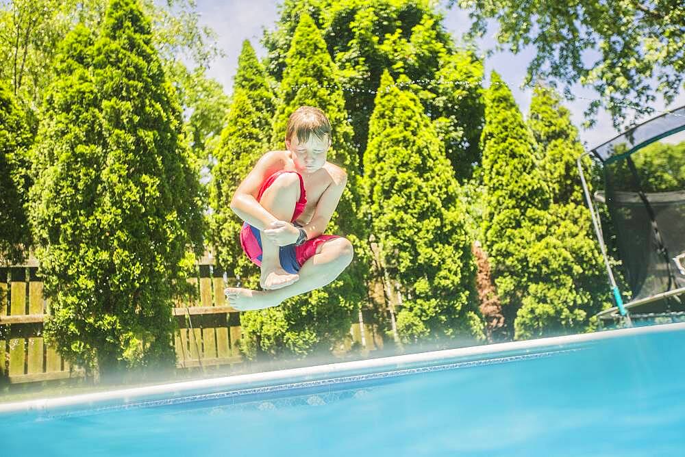 Caucasian boy jumping into swimming pool