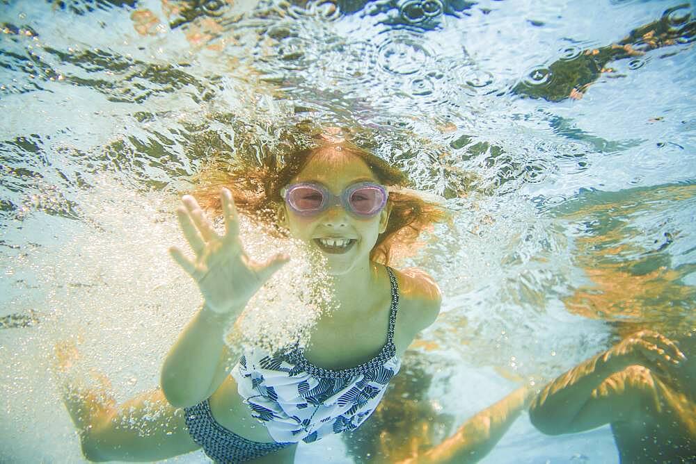 Caucasian girl swimming underwater in swimming pool