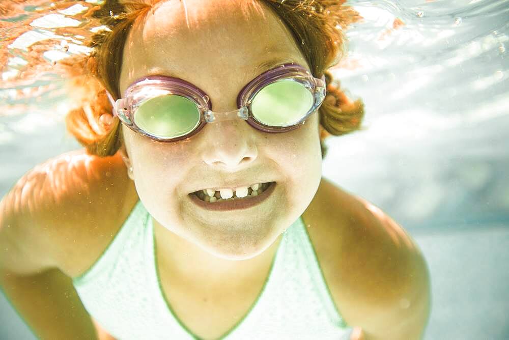 Caucasian girl swimming underwater in swimming pool