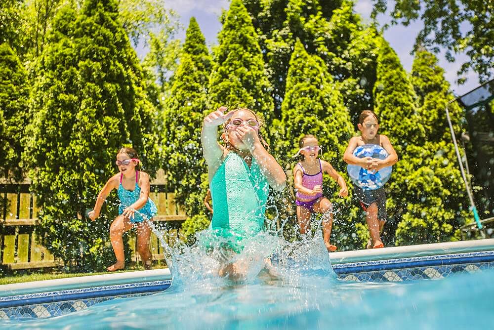 Caucasian girls jumping into swimming pool