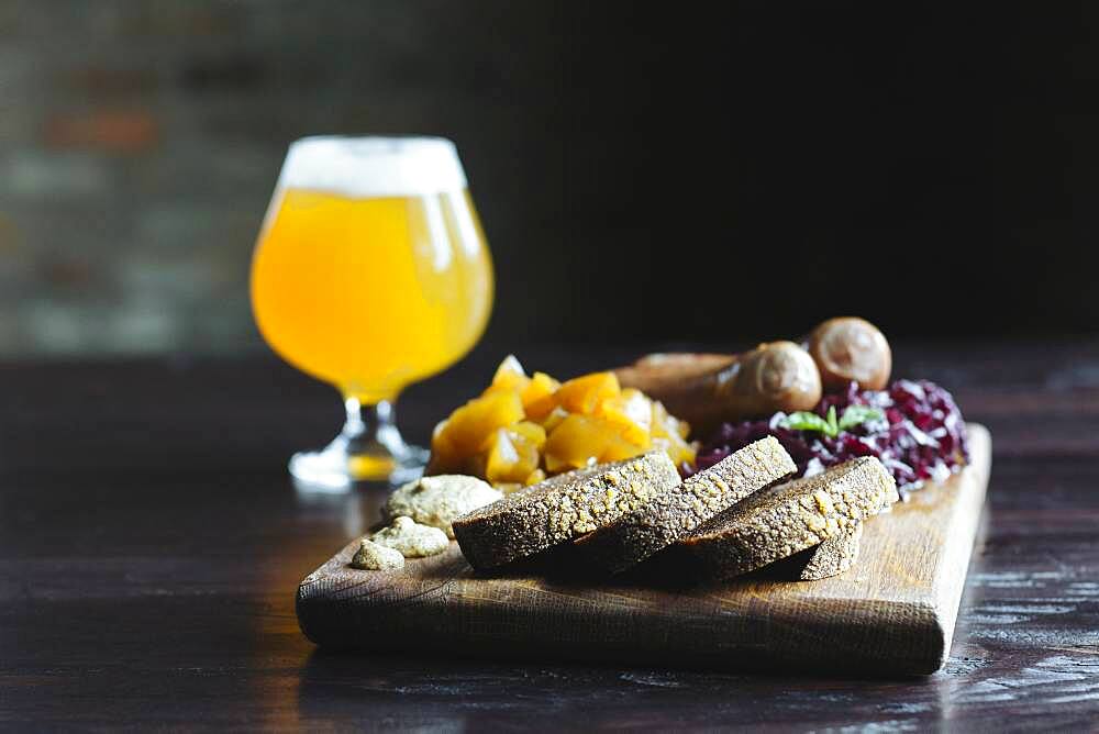 Bread, fruit and cheese on cutting board with beer