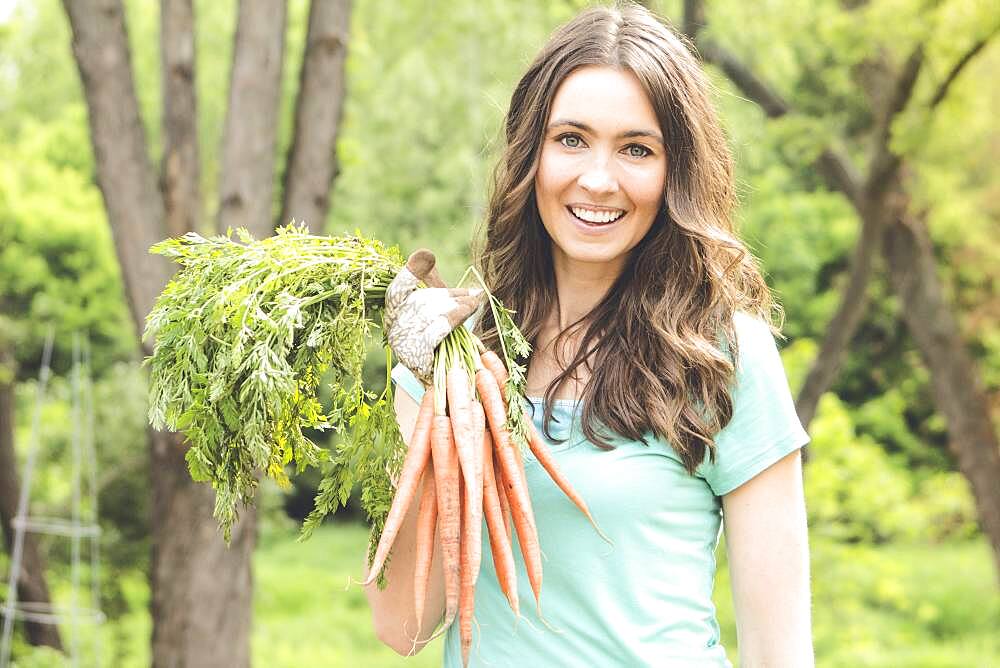 Caucasian woman holding carrots in garden