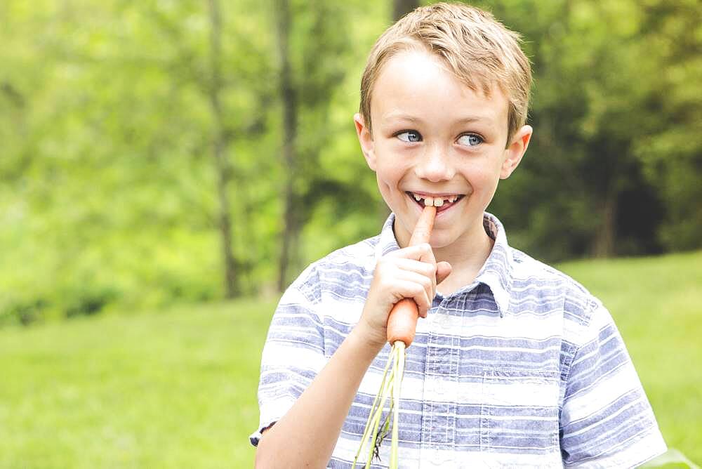 Caucasian boy eating carrot outdoors