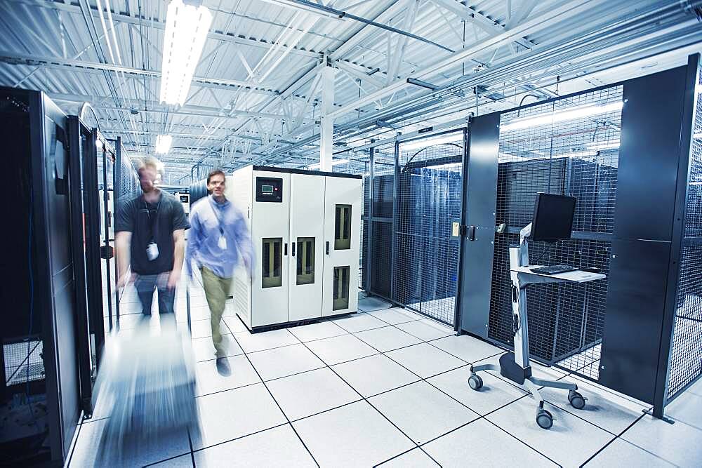 Blurred view of technicians pushing cart in server room