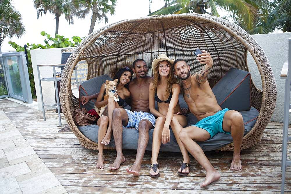 Friends taking selfie with cell phone in cabana