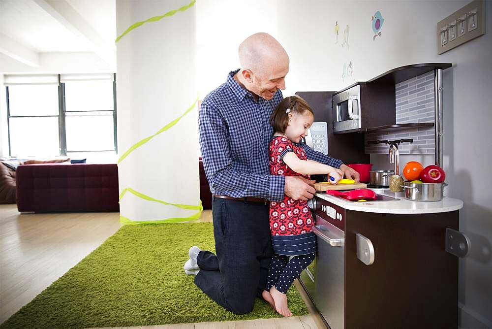 Father and daughter playing in toy kitchen