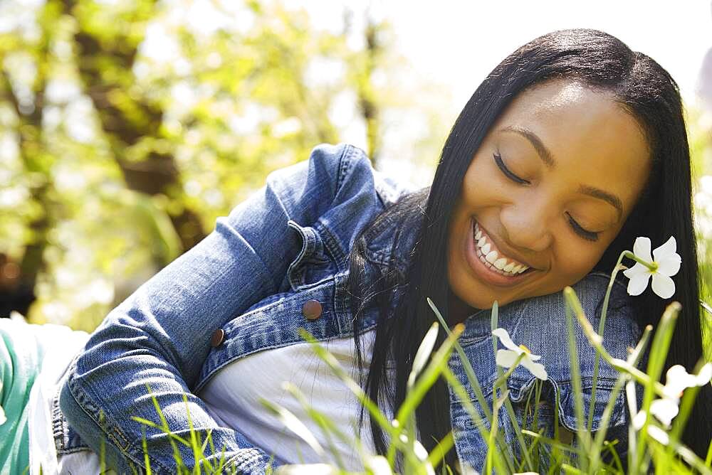 Black woman smiling in grass in park